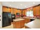 Well-lit kitchen featuring wood cabinets, an island, black appliances, and tile flooring at 4704 Pearcrest Way, Greenwood, IN 46143