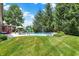 Lush green lawn complements a sparkling blue pool surrounded by lounge chairs and garden, creating a serene backyard retreat at 4704 Pearcrest Way, Greenwood, IN 46143