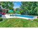 Well-maintained lawn and pool area, complete with lounge furniture, sun umbrellas, and lush landscaping, provide an ideal space for relaxation at 4704 Pearcrest Way, Greenwood, IN 46143