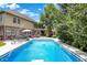 Beautiful backyard pool with diving board and sprayers next to a brick home with a pergola, surrounded by lush greenery at 4704 Pearcrest Way, Greenwood, IN 46143