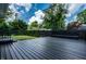 View of the deck and manicured backyard including arborvitae trees and a dark privacy fence at 5660 Crittenden Ave, Indianapolis, IN 46220