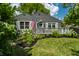 Charming gray home featuring a welcoming front porch, lush landscaping, and an American flag at 5660 Crittenden Ave, Indianapolis, IN 46220