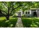 Inviting front entrance of a gray home with lush landscaping, stone walkway and mature shade tree at 5660 Crittenden Ave, Indianapolis, IN 46220