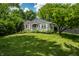 Landscaped front lawn of gray home with a quaint porch and manicured flowerbeds under mature trees at 5660 Crittenden Ave, Indianapolis, IN 46220