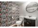 Charming powder room featuring butterfly wallpaper, a round mirror and a sleek vanity with dark cabinetry at 5660 Crittenden Ave, Indianapolis, IN 46220