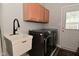 Bright laundry room featuring a utility sink, wood cabinets, and high-efficiency washer and dryer at 6118 Yellow Birch Ct, Avon, IN 46123