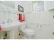 Bathroom with pedestal sink, toilet, window and white paneled walls at 6280 N Chester Ave, Indianapolis, IN 46220