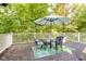Outdoor deck with a dining table, chairs, umbrella, and a view of the wooded backyard at 6280 N Chester Ave, Indianapolis, IN 46220