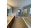 Primary bathroom featuring a double sink vanity, a soaking tub, and a glass shower, all complemented by tiled flooring at 6632 Coppel Ct, Indianapolis, IN 46259