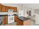 Bright kitchen features wood cabinets, black counters, white appliances, and an island, adjacent to the living area at 8212 Twin River Dr, Indianapolis, IN 46239