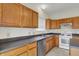Bright kitchen featuring oak cabinets, white appliances, stainless dishwasher and dark countertops at 8212 Twin River Dr, Indianapolis, IN 46239
