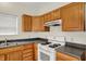 Functional kitchen features wood cabinets, black counters, and white appliances, creating a practical cooking space at 8212 Twin River Dr, Indianapolis, IN 46239