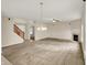 Open-concept living area features neutral carpet, staircase, fireplace, chandelier lighting, and neutral walls at 8212 Twin River Dr, Indianapolis, IN 46239