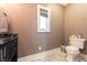 Half-bathroom featuring tile floors, painted walls, new lighting and a toilet next to a window at 9172 W Tulip Dr, Columbus, IN 47201