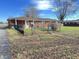 Modest brick home shows a partially fenced backyard with fallen leaves, blue skies, and light cloud cover at 9842 N State Road 9, Pendleton, IN 46064