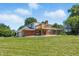 A generous, grassy backyard features a wooden deck, mature trees, and a brick home exterior at 1011 Robin Dr, Anderson, IN 46013