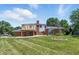 Spacious backyard view with a deck, lush green lawn, mature trees, and a brick home exterior at 1011 Robin Dr, Anderson, IN 46013
