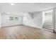 Finished basement featuring wood-look flooring, bright white walls, and staircase with closet doors at 1011 Robin Dr, Anderson, IN 46013