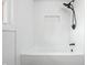 Close-up of a bathtub with white textured tile and a black shower head at 1011 Robin Dr, Anderson, IN 46013