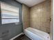 Bathroom featuring a bathtub with tiled walls and a window at 1016 W 31St St, Indianapolis, IN 46208