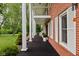 Exterior of a brick home with white columns, shutters, and a covered porch with lush greenery at 10198 N State Road 75, North Salem, IN 46165
