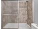 Bathroom shower featuring glass doors and tiled walls, along with a white bathtub and toilet at 1231 N Graham Ave, Indianapolis, IN 46219