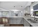Open kitchen with gray cabinets, stone countertops and backsplash, and view into the living room at 1231 N Graham Ave, Indianapolis, IN 46219