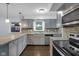 Bright kitchen featuring stainless steel appliances, gray cabinets, and stone countertops and backsplash at 1231 N Graham Ave, Indianapolis, IN 46219