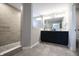 This bathroom features a double vanity, black cabinets, large mirror and walk in shower with tile surround and pebble floor at 14404 Stairbridge Pl, Carmel, IN 46074
