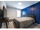 This bedroom is decorated with a blue accent wall, a queen bed and crib, and a dark wood tv table at 14404 Stairbridge Pl, Carmel, IN 46074