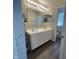 Bathroom featuring double sinks, white cabinets, modern lighting, and wood-look flooring at 2485 Blue Ridge Dr, Greenwood, IN 46143