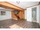 Open basement area with wood-paneled walls, wood-look flooring, and access to a bathroom and stairs at 2606 Shakespeare Dr, Southport, IN 46227