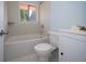 A bathroom with a tub-shower combo, toilet, and vanity with a window providing natural light at 2606 Shakespeare Dr, Southport, IN 46227