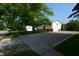 View of the side of this split-level home showcasing its pea gravel driveway and mature trees at 2606 Shakespeare Dr, Southport, IN 46227