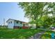 View of the side of this split-level home showcasing its mature trees and street access at 2606 Shakespeare Dr, Southport, IN 46227