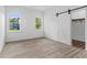 Bedroom with two windows, light wood look floors and a barn door leading to the walk-in closet at 2709 Station St, Indianapolis, IN 46218
