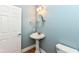 Charming powder room with pedestal sink, round mirror, and light blue walls at 3050 Montgomery Blvd, Lapel, IN 46051