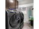 Laundry room featuring modern washer and dryer, storage cabinets, and an ironing board at 3101 N Washington Blvd, Indianapolis, IN 46205