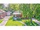 Quaint brick home with a covered front porch, surrounded by lush greenery and a well-manicured lawn at 319 S Webster Ave, Indianapolis, IN 46219