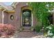 Elegant home entrance with brick facade, arched doorway, and beautiful landscaping at 3893 Bent Tree Ln, Greenwood, IN 46143