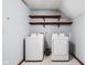 Bright laundry room with white washer and dryer, wooden shelves, and tiled floors at 3893 Bent Tree Ln, Greenwood, IN 46143