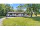 Charming home featuring painted bricks, black trim, natural shutters, and a sprawling green lawn at 4305 Five Points Rd, Indianapolis, IN 46239