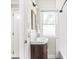 Bathroom featuring dark wood sink cabinet, white tiled walls and a frosted window at 4523 Kingsley Dr, Indianapolis, IN 46205