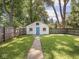 Detached garage with blue door surrounded by a lush green lawn and mature trees at 4523 Kingsley Dr, Indianapolis, IN 46205