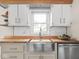 Kitchen with subway tile backsplash, stainless steel sink, wood countertop and white cabinets at 4523 Kingsley Dr, Indianapolis, IN 46205