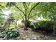 Serene backyard with mature trees, rock garden, and a glimpse of the home's exterior at 4976 Rockne Cir, Carmel, IN 46033
