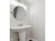 Powder room featuring a pedestal sink, modern lighting, and a circular mirror at 5672 High Timber Ln, Indianapolis, IN 46235