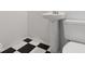 Bathroom with pedestal sink and black and white checkerboard floors, exuding a classic charm at 6009 Ralston Ave, Indianapolis, IN 46220