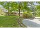 The backyard features a brick house, mature trees, stone wall and gravel driveway at 6430 N Rural St, Indianapolis, IN 46220