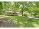 Large backyard featuring lush greenery, mature trees, and a brick house with a chimney at 6430 N Rural St, Indianapolis, IN 46220